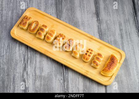 Eine Nahaufnahme von Gourmet-Marzipan-Brötchen-Figuren auf einem Holzteller Stockfoto