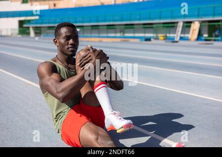 afrikanischer Sportler, der sich auf der Leichtathletik-Strecke aufwärmt Stockfoto