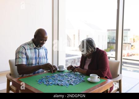 afroamerikanisches Seniorenpaar löst Puzzle zu Hause. Altersruhestandsleben und Lebenskonzept Stockfoto