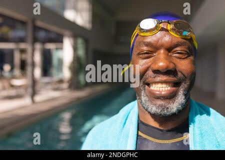 Porträt eines afroamerikanischen Seniorenmannes, der lächelt, während er am Pool steht. Altersruhestandsleben und Lebenskonzept Stockfoto