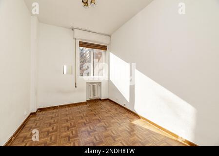 Leeres Zimmer mit Holzfußboden aus Sintasol, eisernem Heizkörper in einer Nische und Innenfenster mit Fensterläden und Aussicht Stockfoto