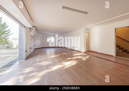 Große leere Garage eines Einzelhauses mit zwei weißen Metallausziehtüren Stockfoto
