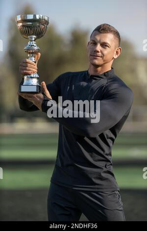 Porträt eines gutaussehenden Sportlers mit einem Becher auf dem Fußballfeld Stockfoto