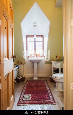Freistehende Badewanne mit Rollbett, Standwaschbecken und Toilette im oberen Badezimmer mit ausgeblichenen Pinienholzböden im alten renovierten Haus aus den 1650er Jahren. Stockfoto