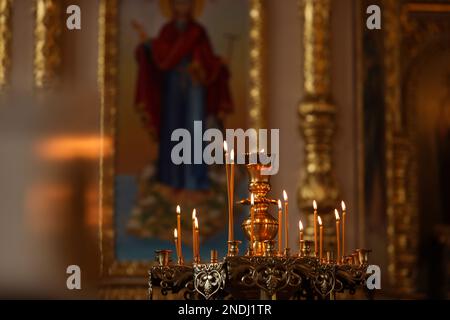 Wunderschöner Stand mit brennenden Kerzen in der Kirche. Taufzeremonie Stockfoto