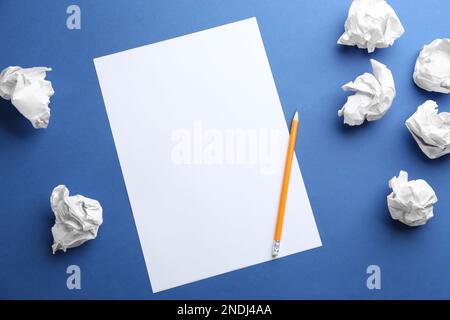 Leeres Blatt, Bleistift und zerknitterte Papierkugeln auf blauem Hintergrund, flach liegend. Platz für Text Stockfoto