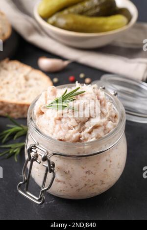 Köstlicher Schmalzaufstrich im Glas auf dem schwarzen Tisch Stockfoto