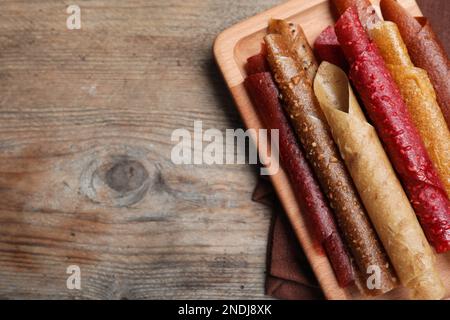 Köstliche Fruchtlederrollen auf einem Holztisch, Draufsicht. Platz für Text Stockfoto