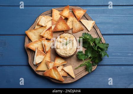 Köstliche Pita-Chips mit Hummus auf blauem Holztisch, Blick von oben Stockfoto