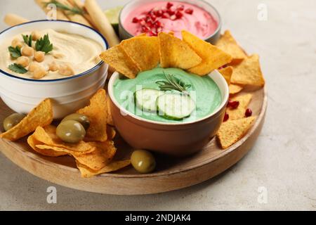 Verschiedene Arten von leckerem Hummus serviert mit Snacks auf einem leichten Tisch Stockfoto