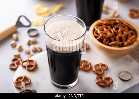 Dunkles, kräftiges Bier in hohen Gläsern, Bier und Snacks auf dem Tisch Stockfoto