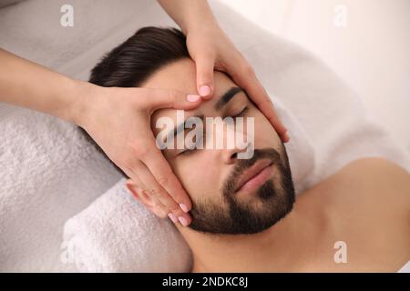 Junger Mann, der eine Gesichtsmassage im Schönheitssalon bekommt, von oben Stockfoto