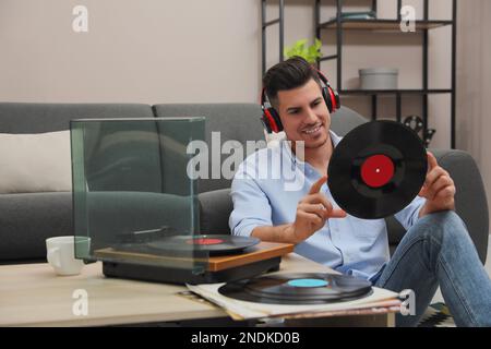 Glücklicher Mann, der zu Hause Musik mit Plattenspieler hört Stockfoto
