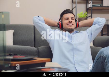 Glücklicher Mann, der zu Hause Musik mit Plattenspieler hört Stockfoto