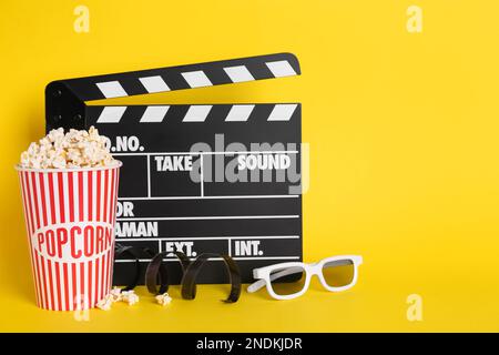 Köstliches Popcorn, 3D-Gläser, Klebeband und Klappbrett auf gelbem Hintergrund Stockfoto