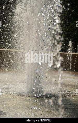 Schwebendes Wasser tropft aus der Luft aus einem unscharfen Brunnen Stockfoto