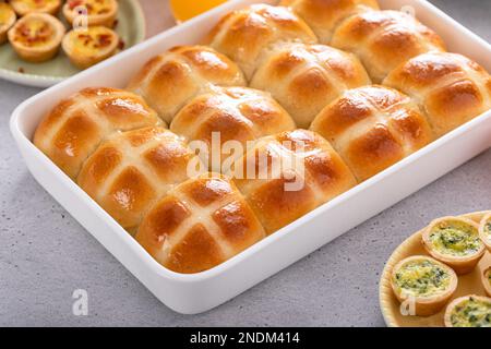 Traditionelle Brötchen mit heißem Kreuz, frisch gebacken für den Osterbrunch in einer Pfanne Stockfoto
