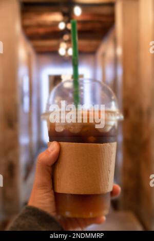 Handgehaltener Eiskaffee mit orangefarbenem Stockfoto Stockfoto