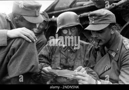 Ein Soldat aus der SS-Panzerdivision 'Totenkopf' von 3. und ein Soldat aus der Infanteriedivision von 228, der Befehle an der Ostfront diskutiert. Stockfoto