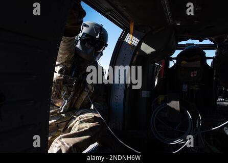 EIN US-AMERIKANISCHER Army Soldier, dem 3. Angriffshikopter-Bataillon, 1. Luftfahrtregiment in Fort Riley, Kansas, zugeteilt, klettert während eines gemeinsamen Trainings am McConnell Air Force Base, Kansas, am 3. Februar 2023 in einen UH-60 Blackhawk. Airmen der 22. Sicherheitsstaffel trainierten mit den Soldaten, um taktische Starts und Landungen im Blackhawk zu üben. (USA Air Force Foto von Staff Sgt. Tryphena Mayhugh) Stockfoto