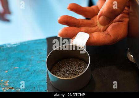 Arbeiter schüttet Schießpulver in die Metallschüssel auf dem Tisch in der Fabrik Stockfoto