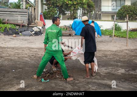 Bali, Indonesien - 15. Februar 2023: Unbekannte Männer, die den Strand in Bali, Indonesien, säubern. Stockfoto