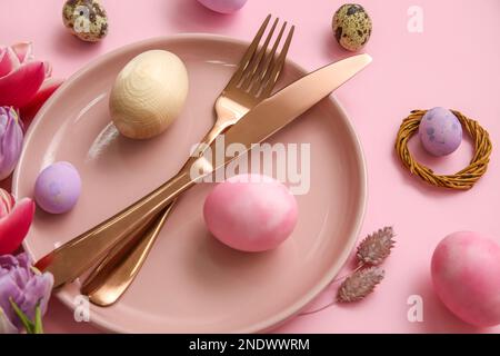 Tisch mit Ostereiern auf pinkfarbenem Hintergrund, Nahaufnahme Stockfoto