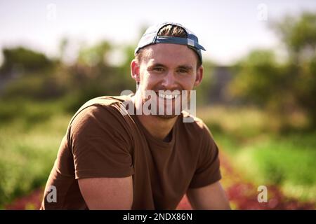 Auf einer Farm ist das Leben viel besser. Porträt eines gutaussehenden jungen Landwirts, der sich auf seiner Farm selbstbewusst und glücklich fühlt. Stockfoto