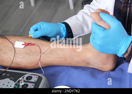 Elektromyographie an den unteren Extremitäten, graphische Aufzeichnungstechnik der elektrischen Aktivität des Musculus tibialis durch einen Spezialisten ne Stockfoto