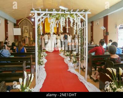 Braut, die den Kapellgang entlang läuft, roter Teppich auf einer katholischen philippinischen Hochzeit. Stockfoto