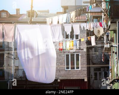 Kleidung hängt zum Trocknen an der Wäscheleine im Freien im Hof von Häusern. Wäschetrocknung in Georgia. Stockfoto