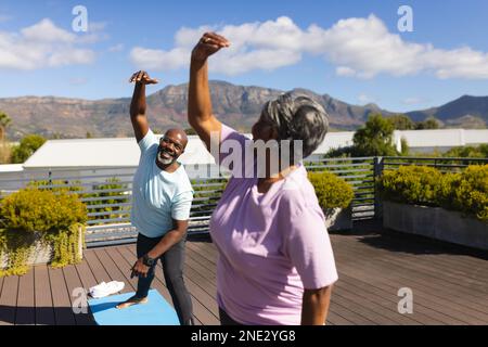 afroamerikanisches Seniorenpaar, das auf der Terrasse zu Hause Stretching-Übungen durchführt. Altersruhestandsleben und Lebenskonzept Stockfoto
