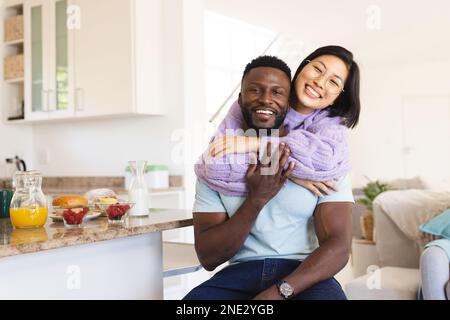 Porträt eines glücklichen, vielfältigen Paares, das in der Küche umarmt. Verbringen Sie Zeit zu Hause, in Ihrem Haushalt und in Ihrem Lebensstil. Stockfoto