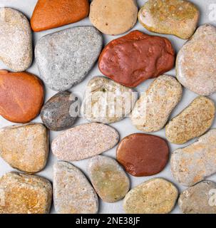 Textur aus flachen Flusssteinen auf grauem Hintergrund. Stockfoto