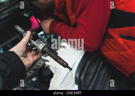 Ein Mann, der eine im Dieselmotor festsitzende Einspritzdüse mit einer Presse entfernt. Hochwertiges Foto Stockfoto