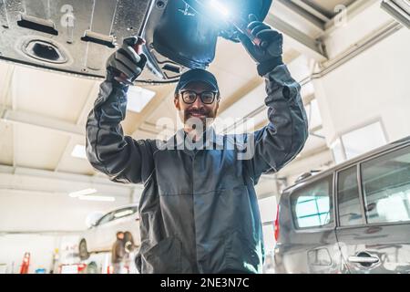 Mittlere Aufnahme eines Mechanikers in der Mitte des Werkstücks. Posieren für ein Foto. Werkstattkonzept. Hochwertiges Foto Stockfoto