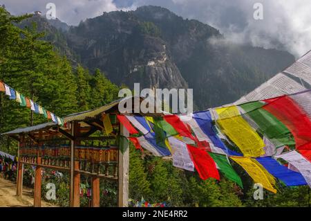 Traditionelle Gebetsmühlen und Gebetsflaggen auf dem Weg zum buddhistischen Kloster Paro Taktsang, auch bekannt als Tigernest im Westen Bhutans Stockfoto