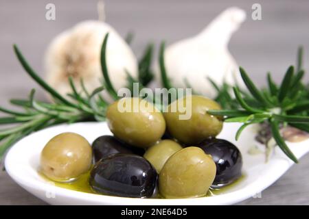 Rosmare Zweige, Knoblauch und Oliven auf einem Teller Stockfoto