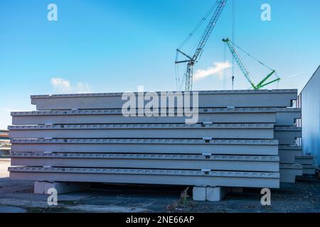 Betonplatten auf Baustellen gestapelt. Turmkräne im Hintergrund. Stockfoto