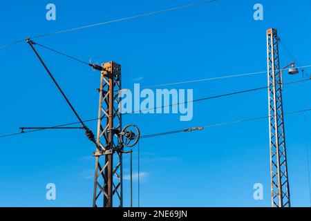 Elektrische Leitungen an Metallmasten über der Eisenbahn. Klarer blauer Himmel. Stockfoto