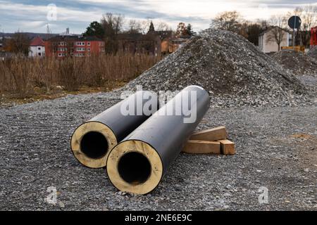 Auf der Baustelle liegen abgeschnittene Rohre mit Wärmedämmung. Schutt im Hintergrund. Stockfoto