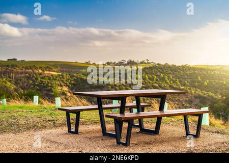 Öffentlicher Picknicktisch mit McLaren Vale Weinbergen im Hintergrund bei Sonnenuntergang, Südaustralien Stockfoto