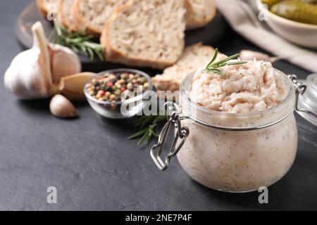 Köstlicher Schmalzaufstrich im Glas auf dem schwarzen Tisch Stockfoto