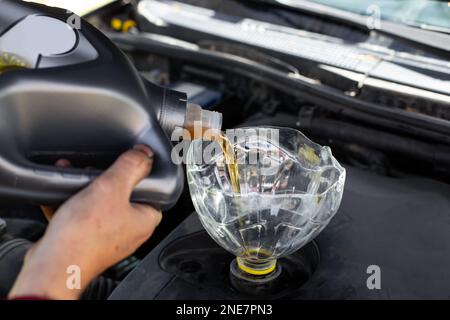 Der Automechaniker gießt Motoröl durch den Trichter in den Motor. Ölwechsel im Auto. Stockfoto