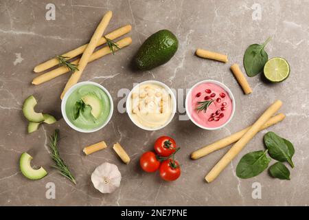 Flache Liegezusammensetzung mit verschiedenen köstlichen Hummusen auf braunem Marmortisch Stockfoto