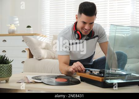 Glücklicher Mann, der zu Hause Musik mit Plattenspieler hört Stockfoto