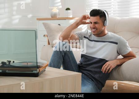Glücklicher Mann, der zu Hause Musik mit Plattenspieler hört Stockfoto
