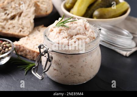 Köstlicher Schmalzaufstrich im Glas auf dem schwarzen Tisch Stockfoto