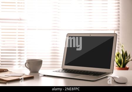 Moderner Laptop auf Tisch im Innenbereich. Komfortabler Arbeitsplatz Stockfoto