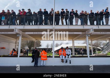 Zuschauer stehen auf dem Dach der Pit Lane und Marshals sitzen auf der Pit Lane Wall, 79. Mitgliederversammlung, Goodwood Motor Racing Circuit, Großbritannien Stockfoto